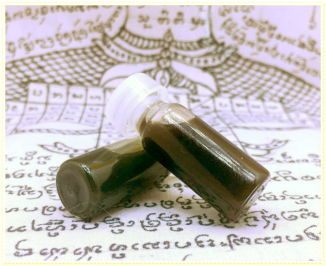 Two small glass vials of dark ritual oil on Thai script cloth by Thai Blessing Co passion oil for couples