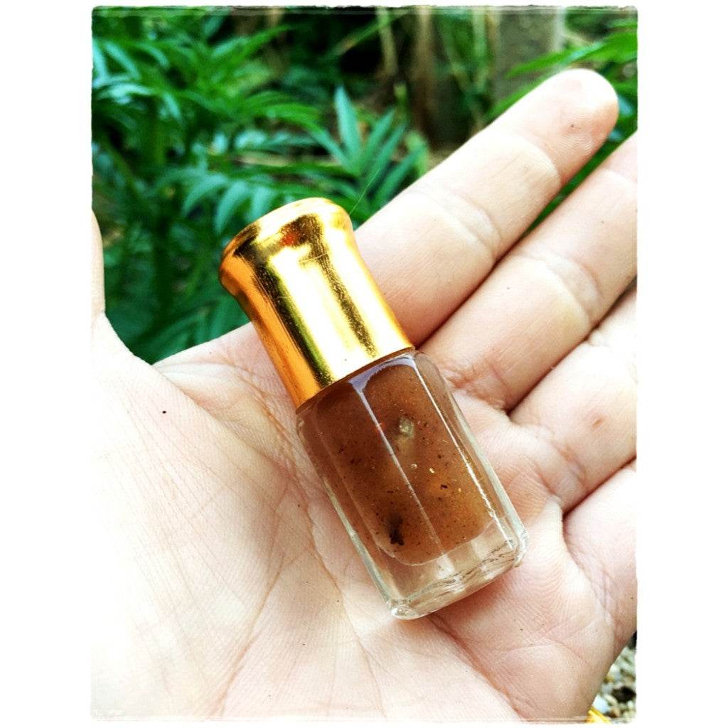 Thai love attraction oil brown herbal roll on bottle with gold cap in hand by Thai Blessing Co