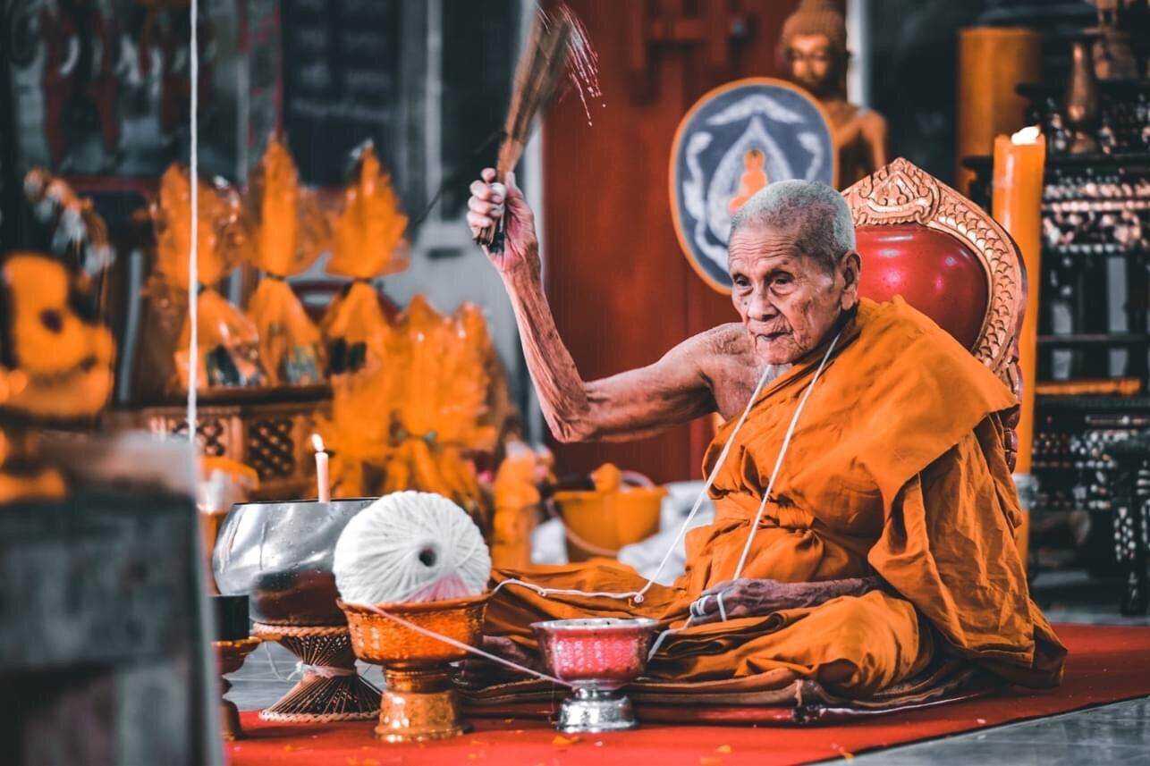 Thai monk performing blessing at temple altar with Phra Pidta Maha Uthom Amulet - Yung Yan (One of Siam's Sacred Symbols)