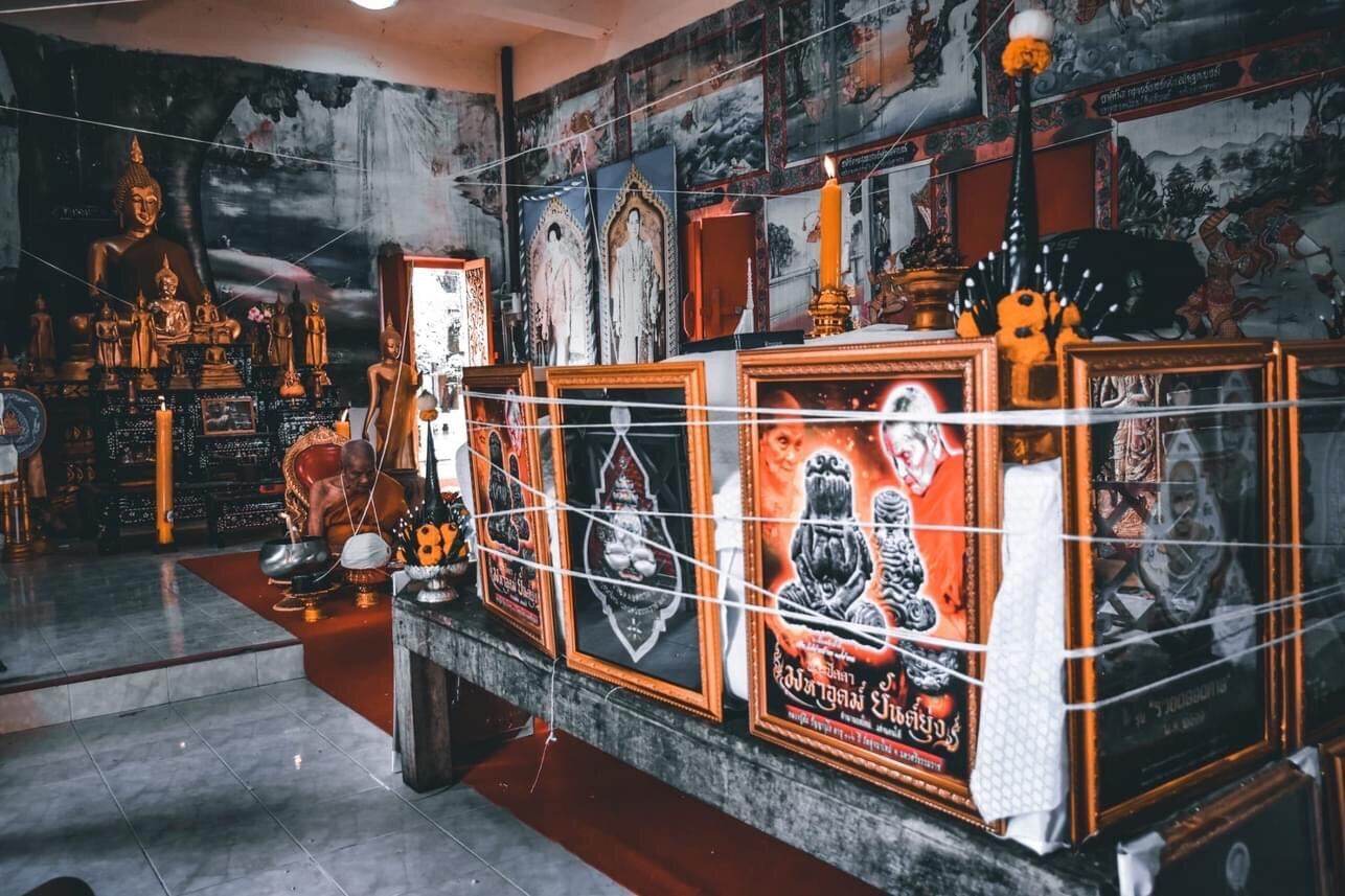 Temple display of Phra Pidta Maha Uthom Amulet - Yung Yan (One of Siam's Sacred Symbols) with framed icons and candles
