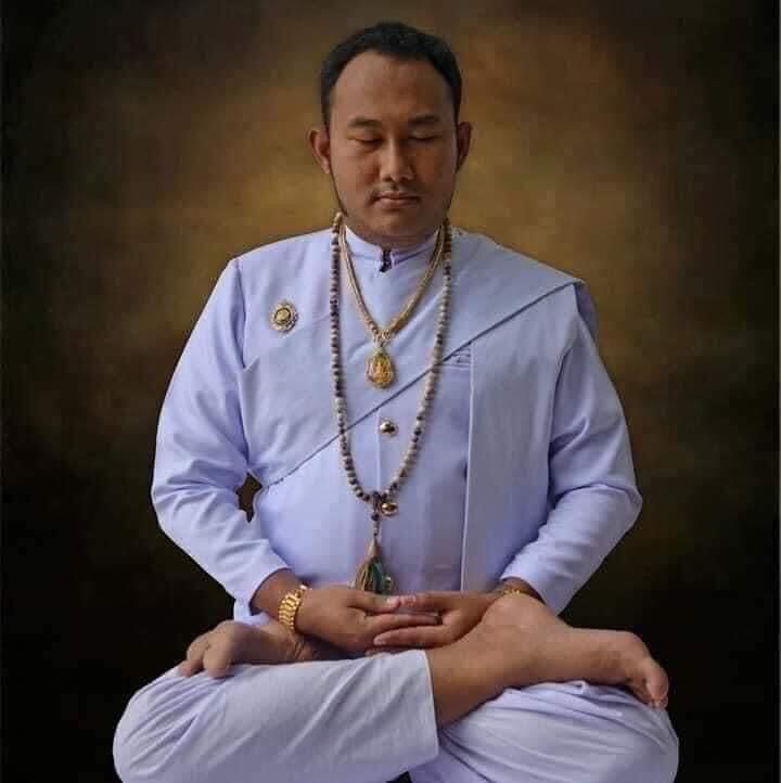 Thai monk in white robes meditating with amulets and prayer beads for black magic neutralizing herbal medicine