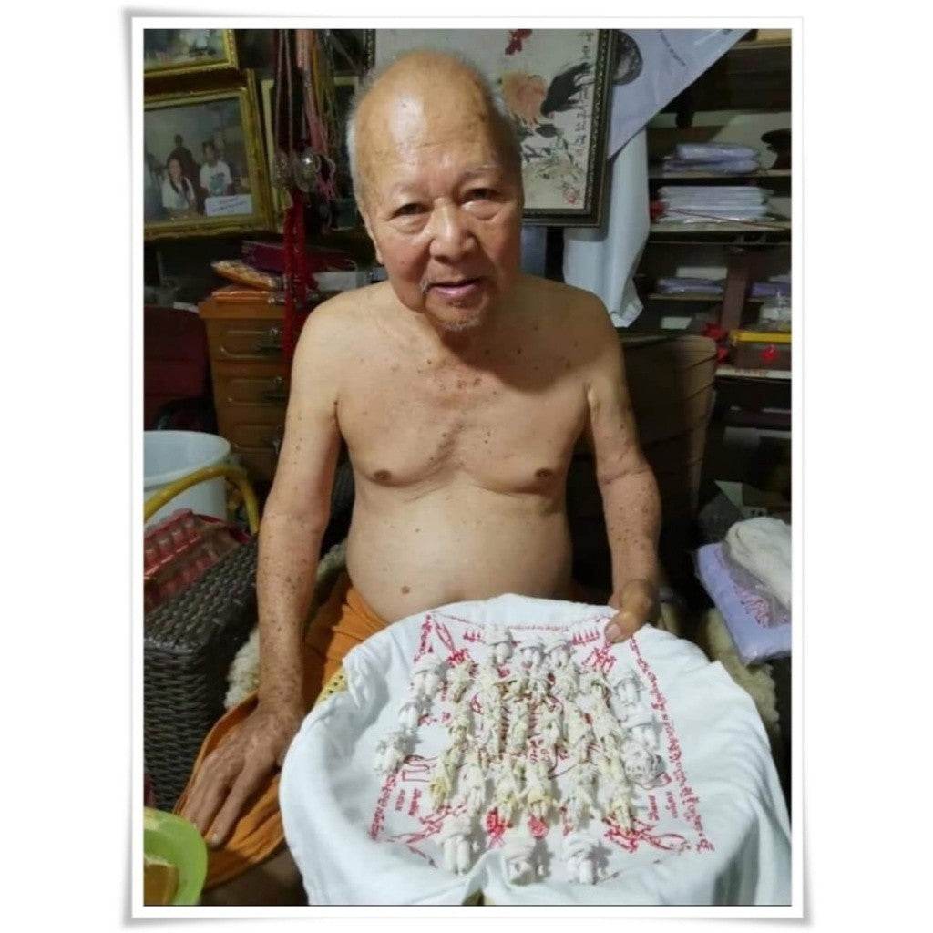 Elderly monk holding a crafted spiritual amulet for attraction and relationship on a white cloth