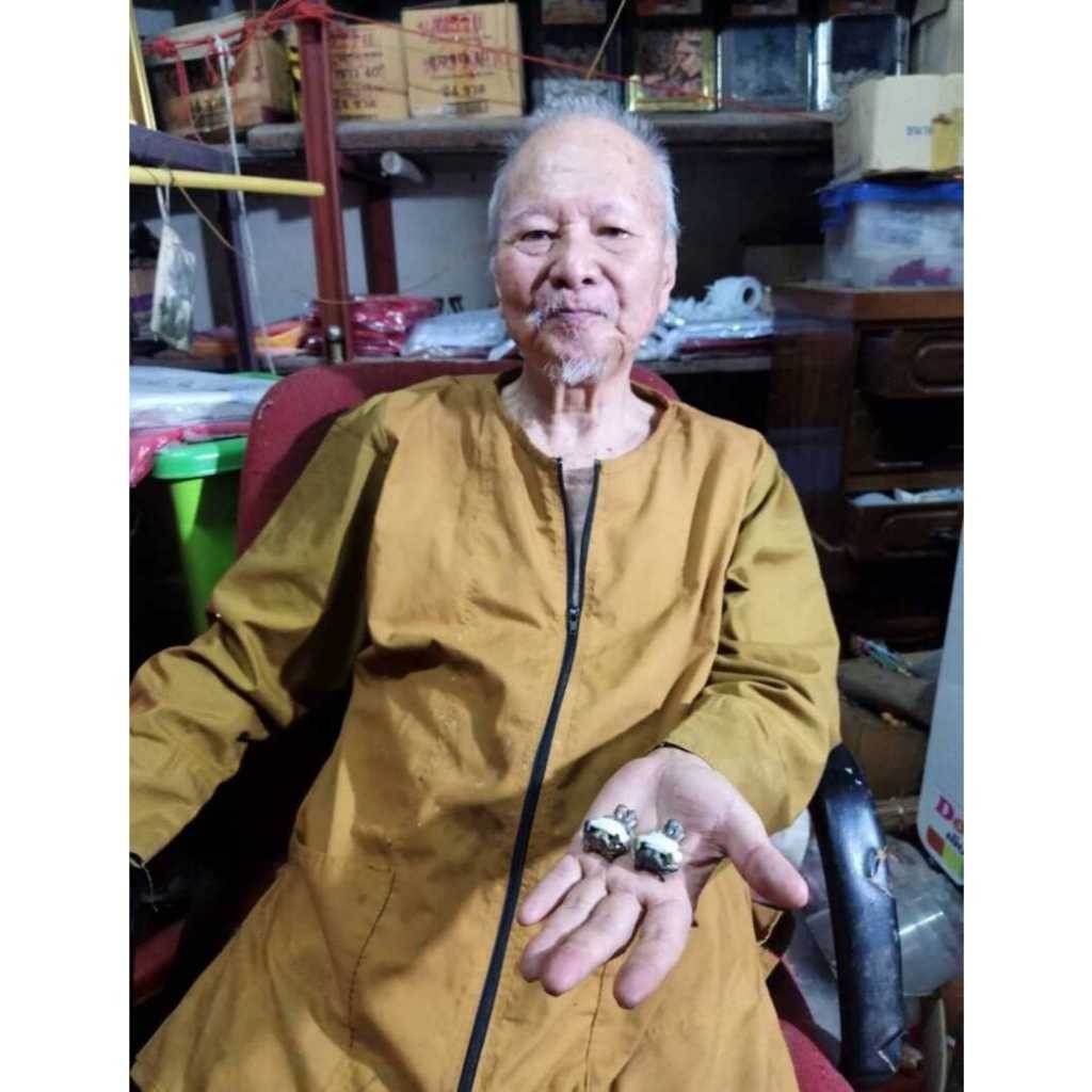 Elderly man holding spiritual amulet for attraction and relationship in his hand in a cozy indoor setting