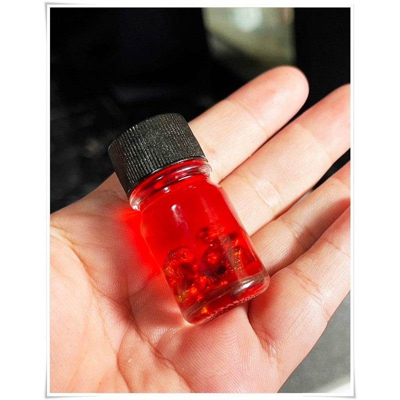 Thai Blessing Co spiritual oil for rekindling love in a small red glass vial on a hand
