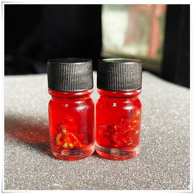 Two bottles of Thai Blessing Co spiritual oil for rekindling love with vibrant red color and unique contents