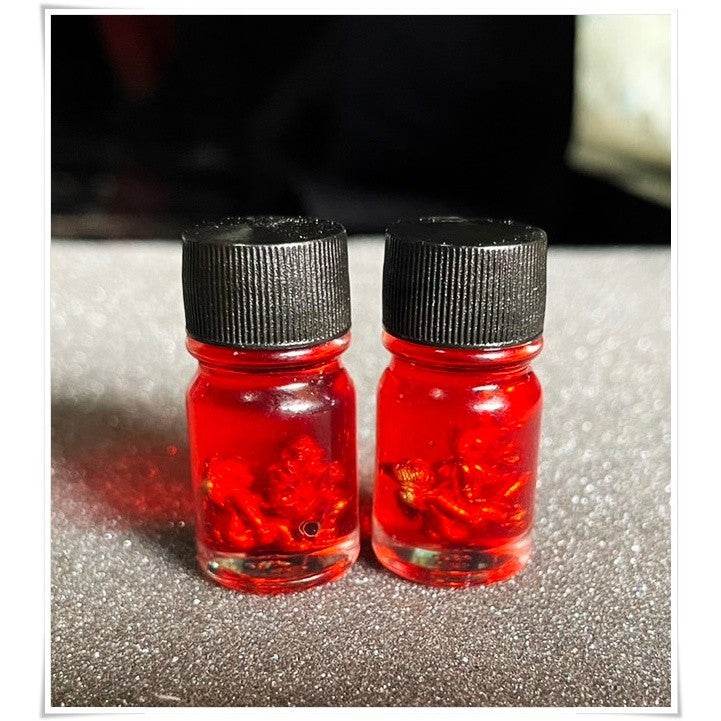 Two bottles of Thai Blessing Co spiritual oil for rekindling love in vibrant red with unique contents