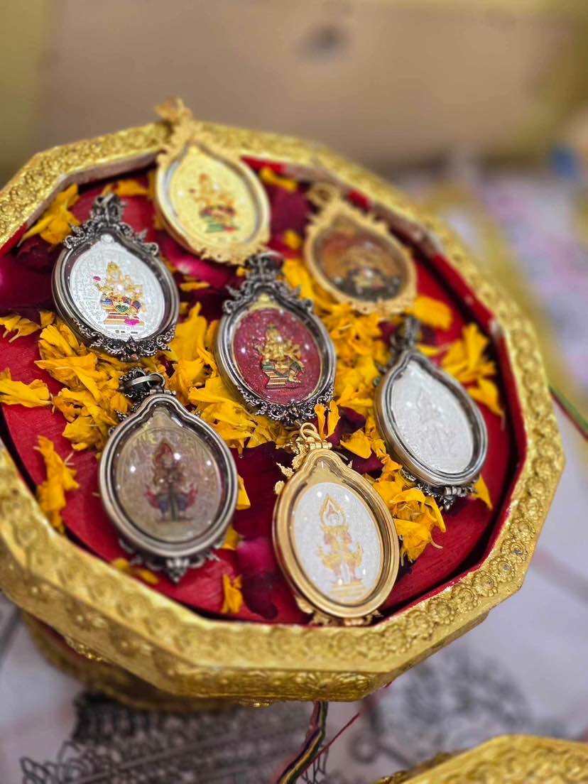 Collection of Supreme Brahma amulet by Phra Ajarn Weeraphon displayed in an ornate tray with red fabric and marigold petals
