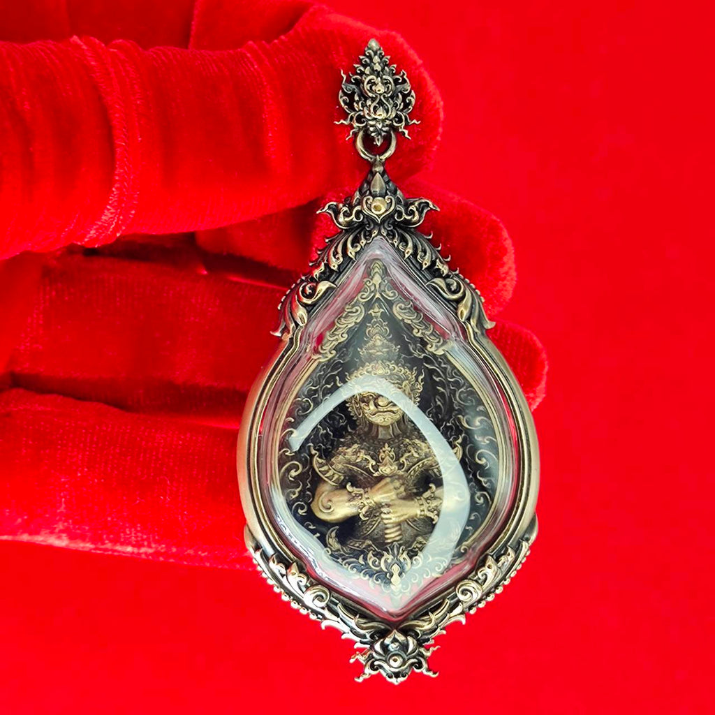 Tao Wessuwan amulet for protection in a decorative case held by a gloved hand, featuring intricate design.