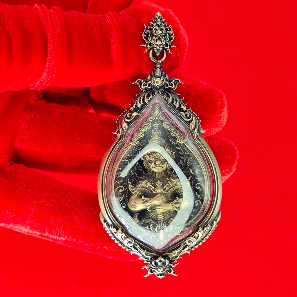 Elegant Tao Wessuwan amulet for protection housed in a decorative frame, held with red gloves