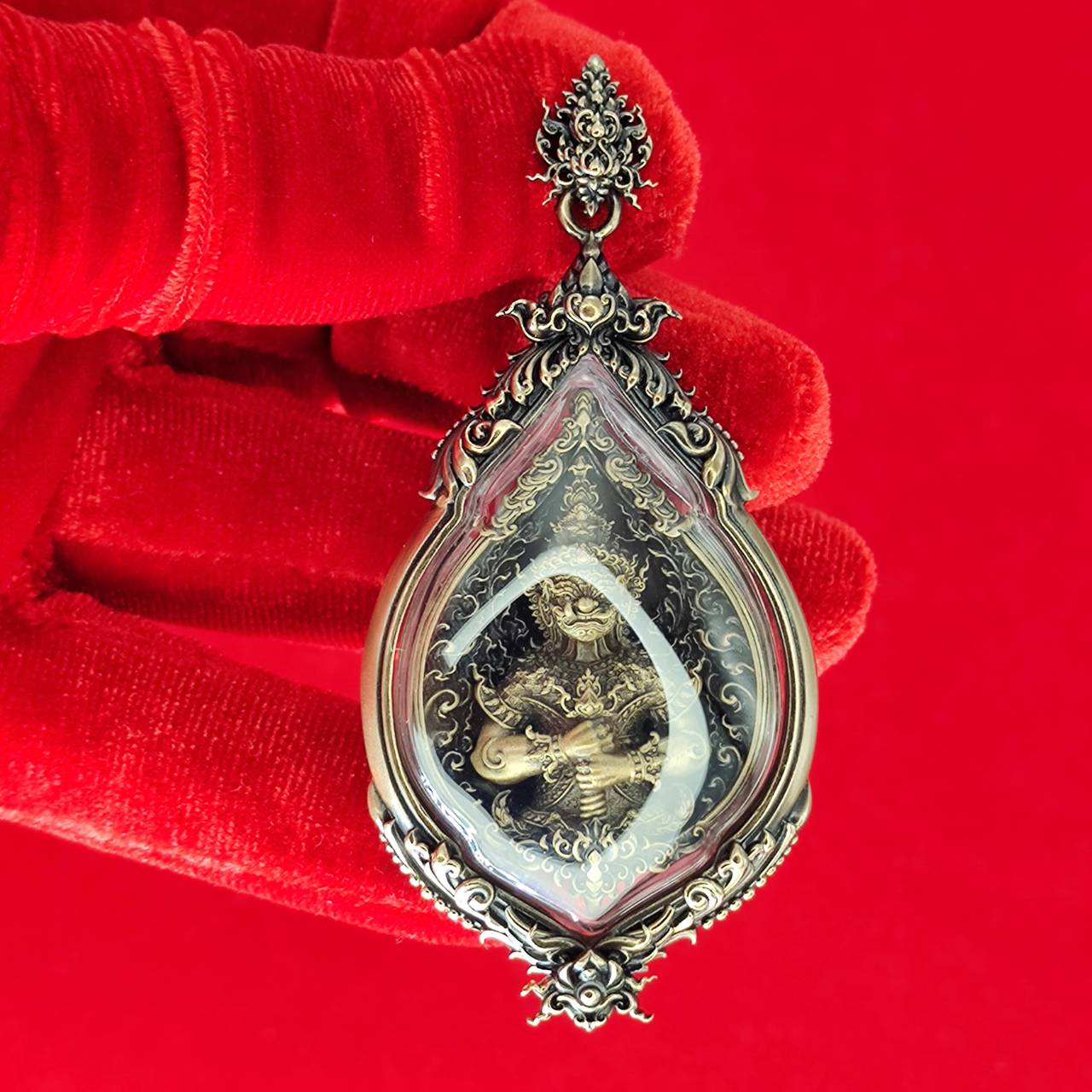 Tao Wessuwan amulet for protection in ornate silver casing with intricate design, shown against a red background