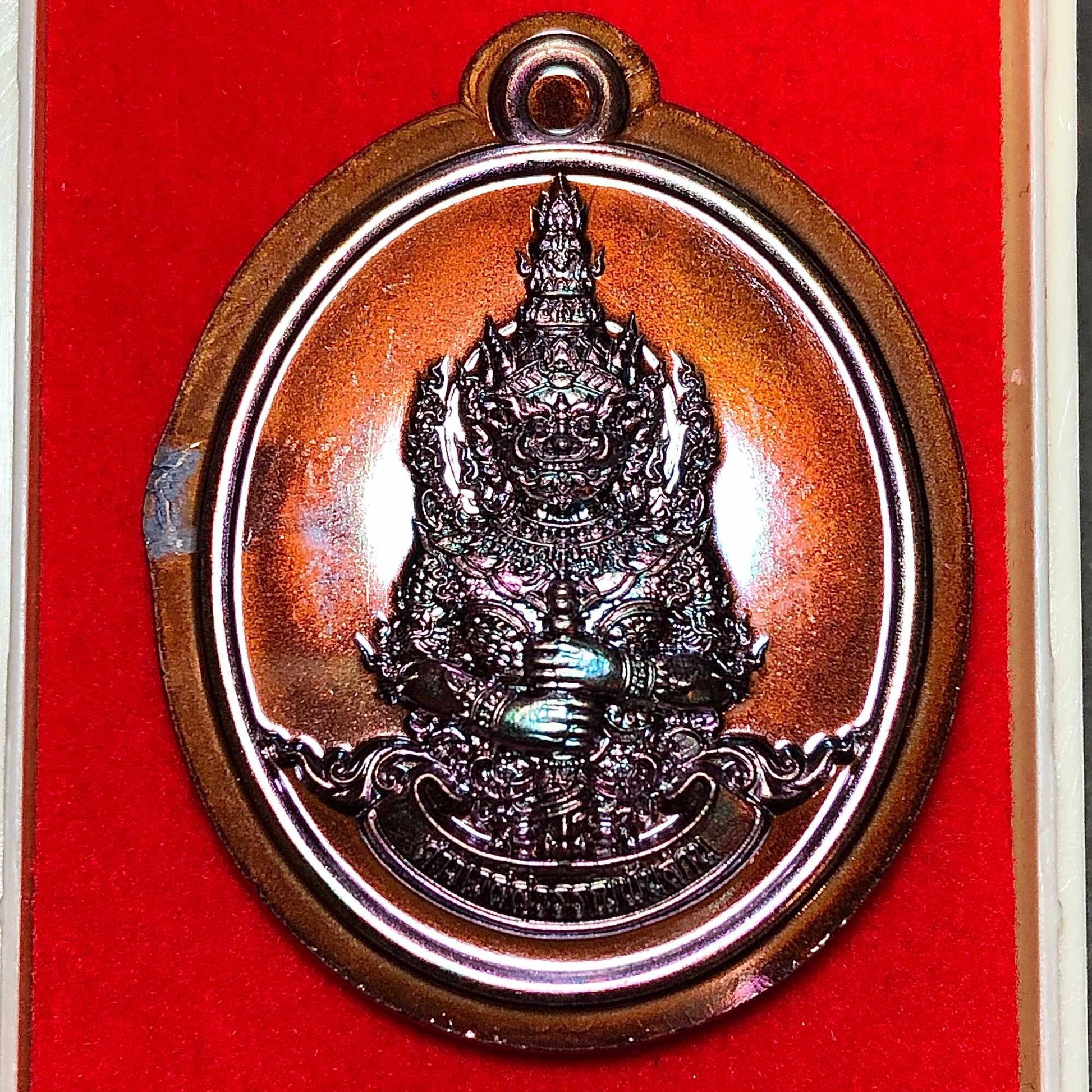 Tao Wessuwan amulet for wealth in bronze finish, detailed design on a red velvet background