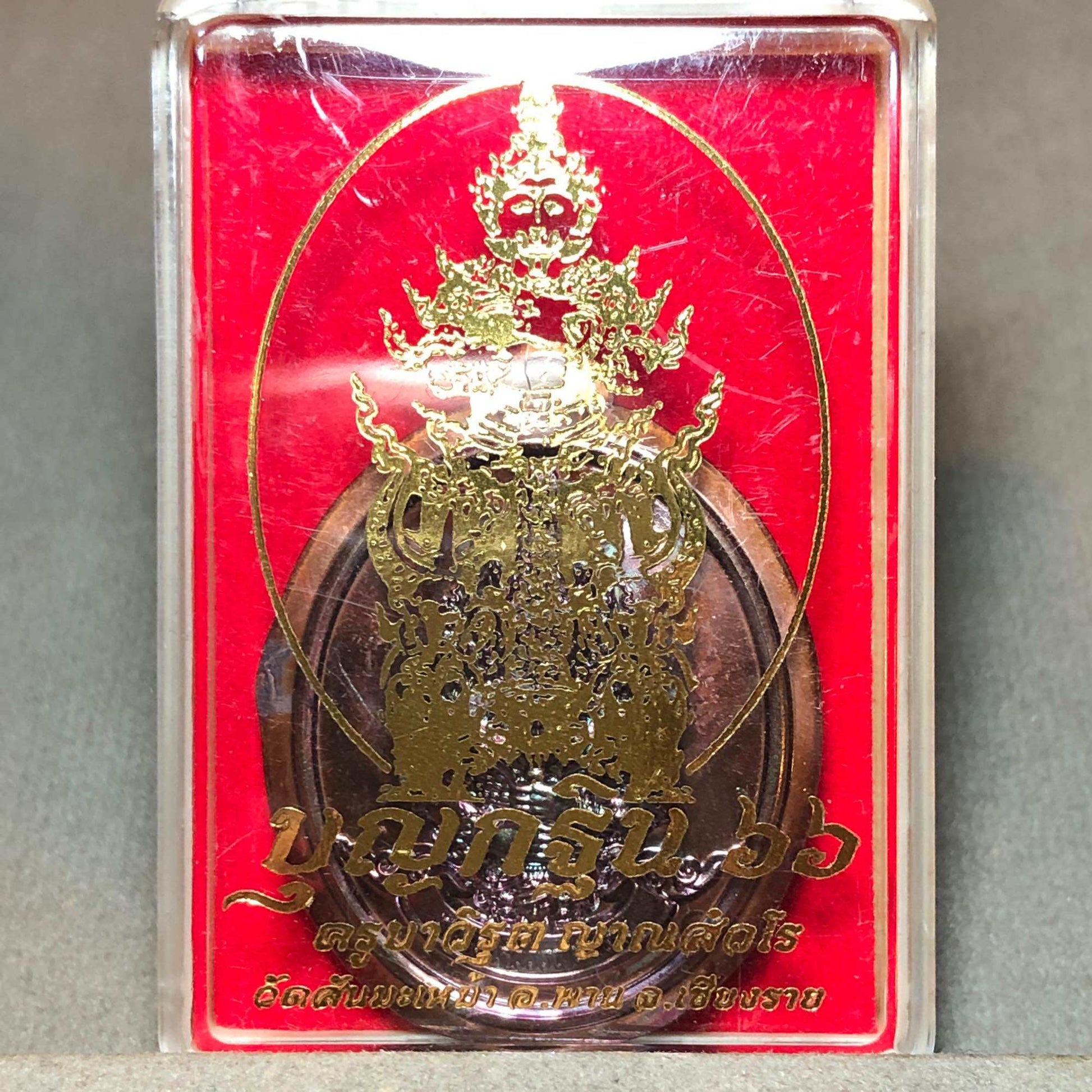 Tao Wessuwan amulet for wealth in a clear case with gold detailing and red background