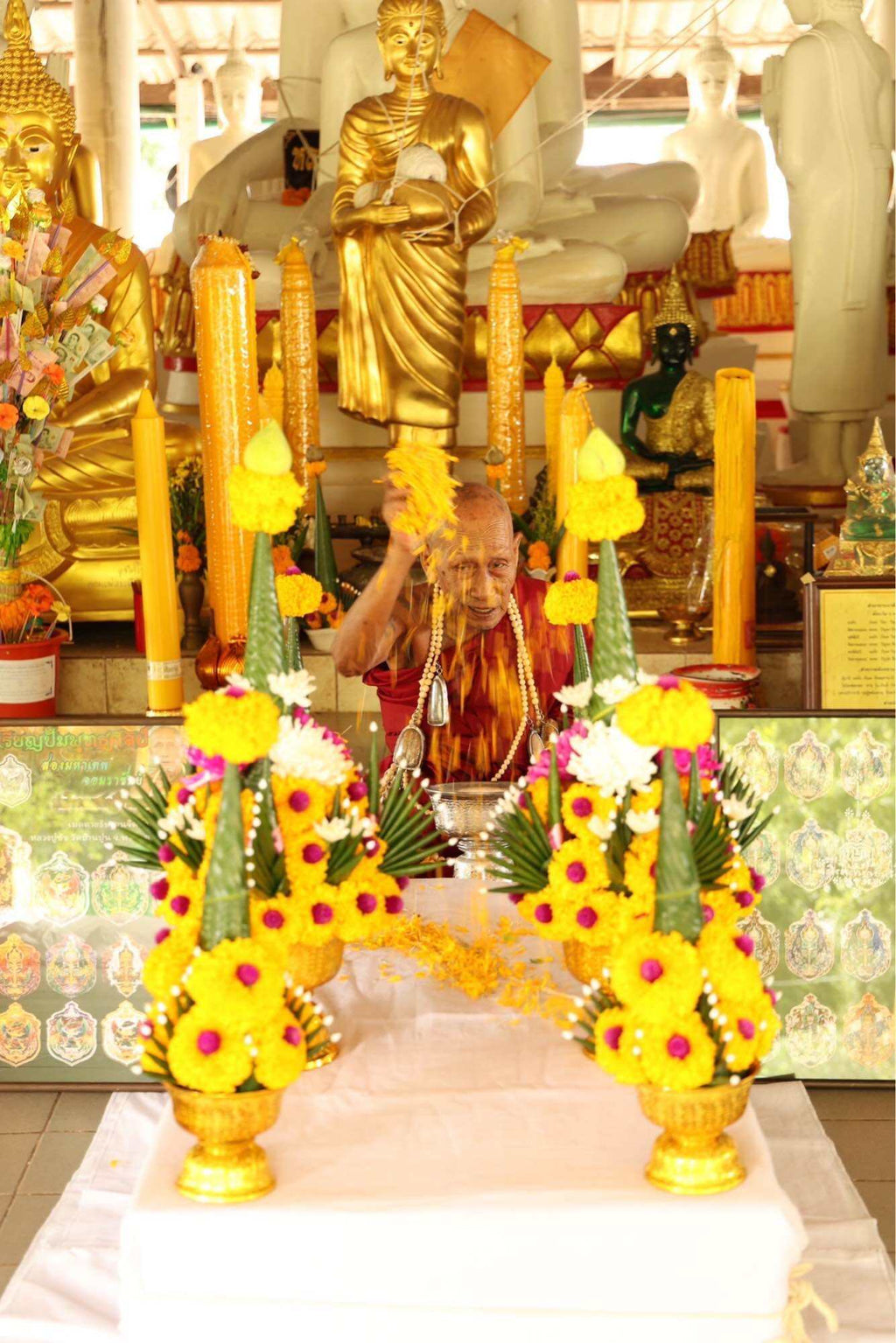 Ceremonial setup with Tao Wessuwan Garuda amulet and floral offerings in a temple setting