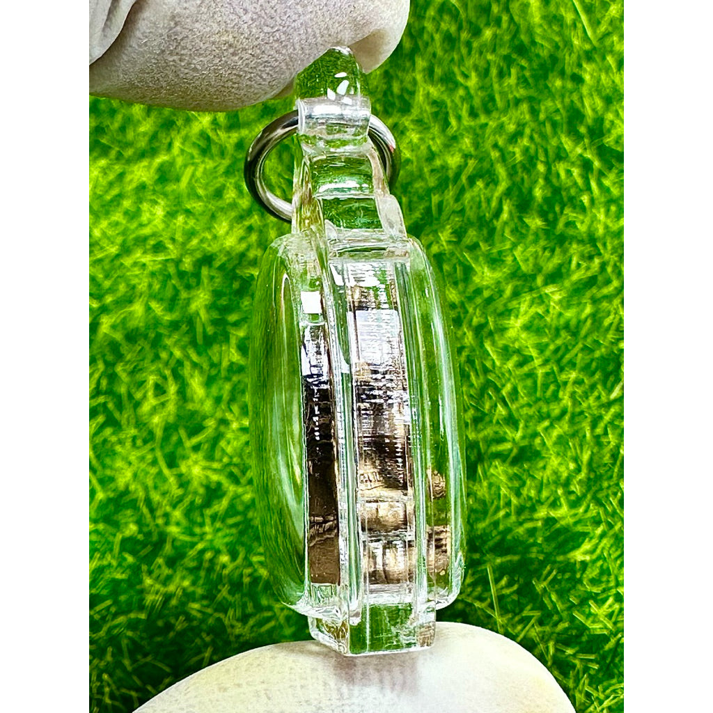 Side view of Taowessuwan amulet blessed by monk in a clear protective case with metal ring