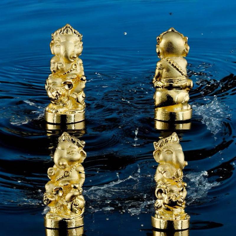Gold Ganesha blessing amulet Thailand in four angles placed on water with ripples