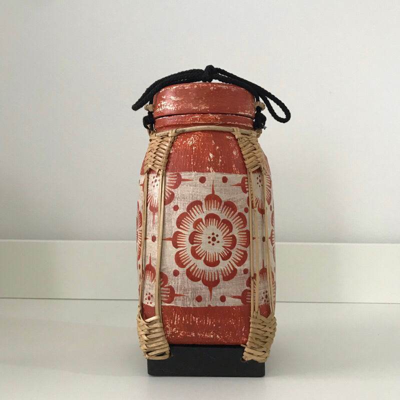 Handmade lanna bamboo rice box with traditional red floral pattern and black carrying string