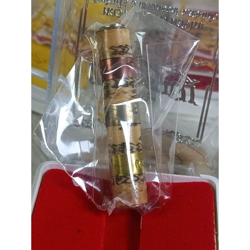 Thai fortune charm bracelet with traditional script wrapped in clear plastic packaging on red cushion