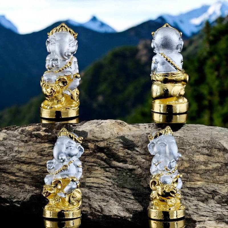 Ganesha blessing amulet Thailand with gold and silver detailing displayed on a rock with mountain background