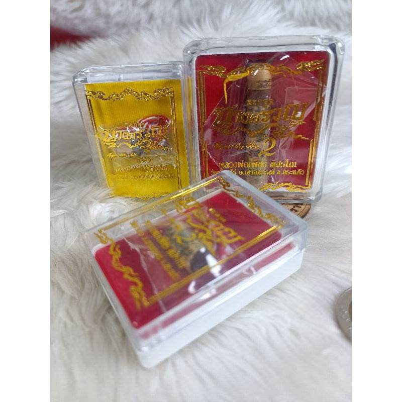 Thai fortune charm bracelet in decorative red and gold clear plastic cases displayed on white fabric