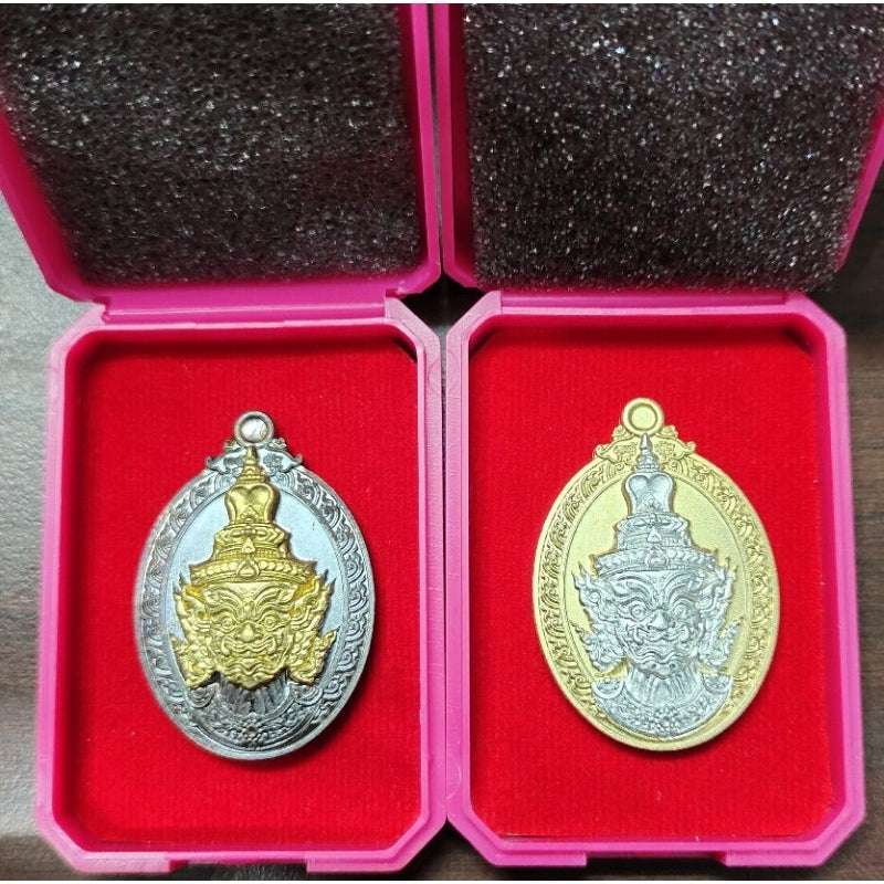 Two Thaweesuwan wealth blessing amulet in silver and gold tones displayed in red velvet boxes
