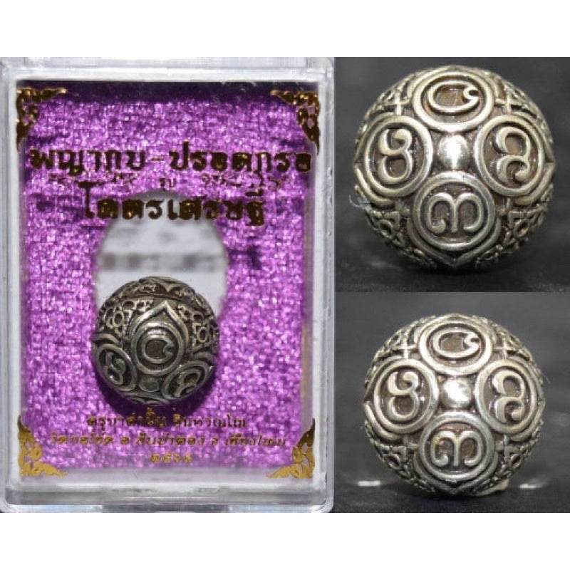 Thai Blessing Co ancient mercury spirit orb silver talisman with Thai script motifs in display case on purple velvet