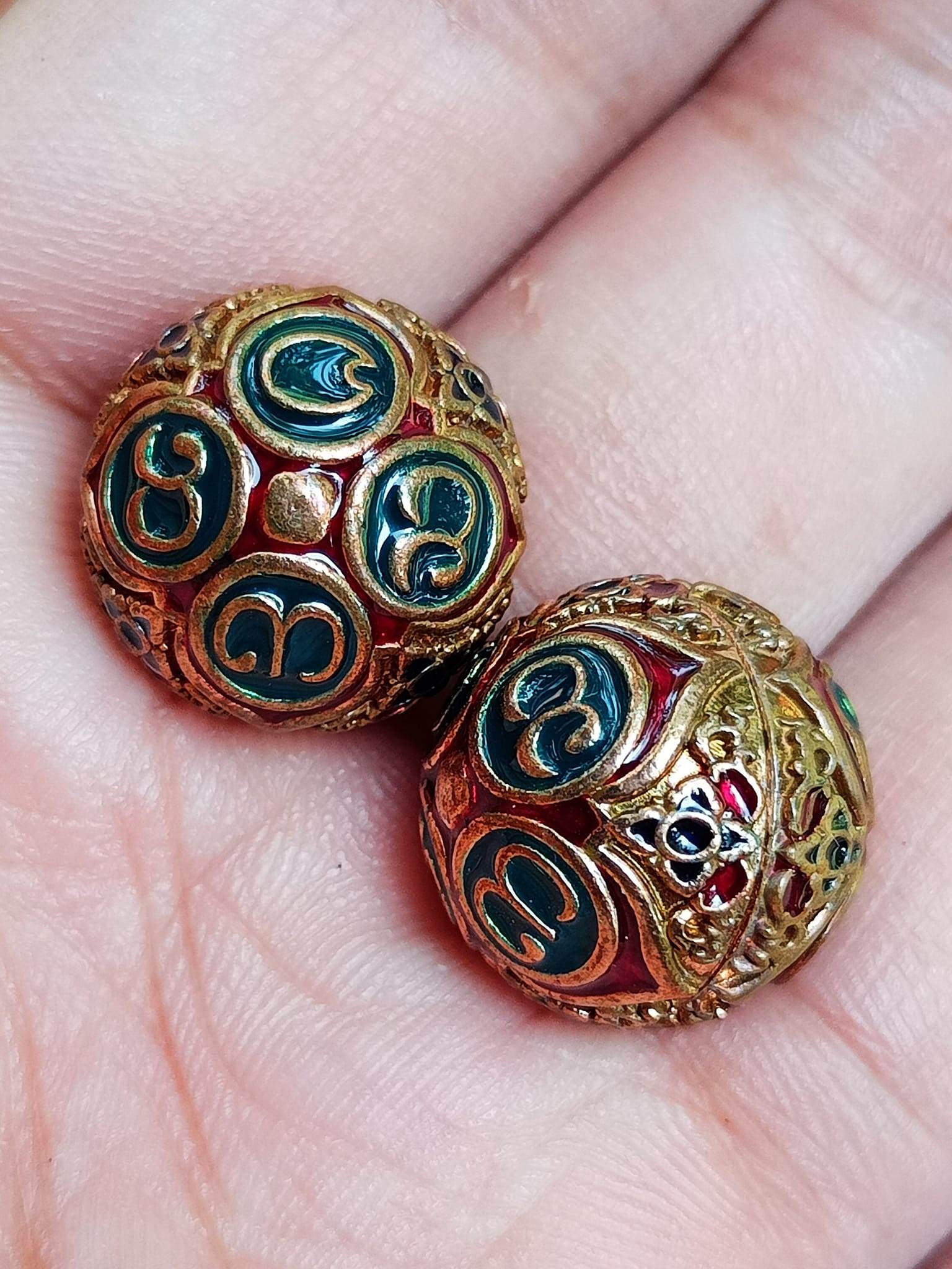 Two ornate gold filigree spheres with teal script symbols in a palm ancient mercury spirit orb feng shui talismans
