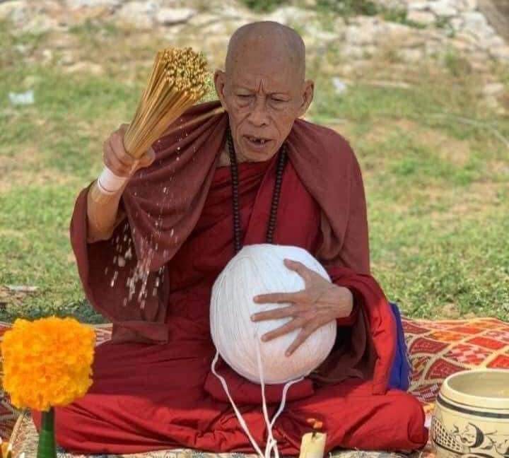 Thai monk blessing an ancient mercury spirit orb white sphere for home feng shui and protection