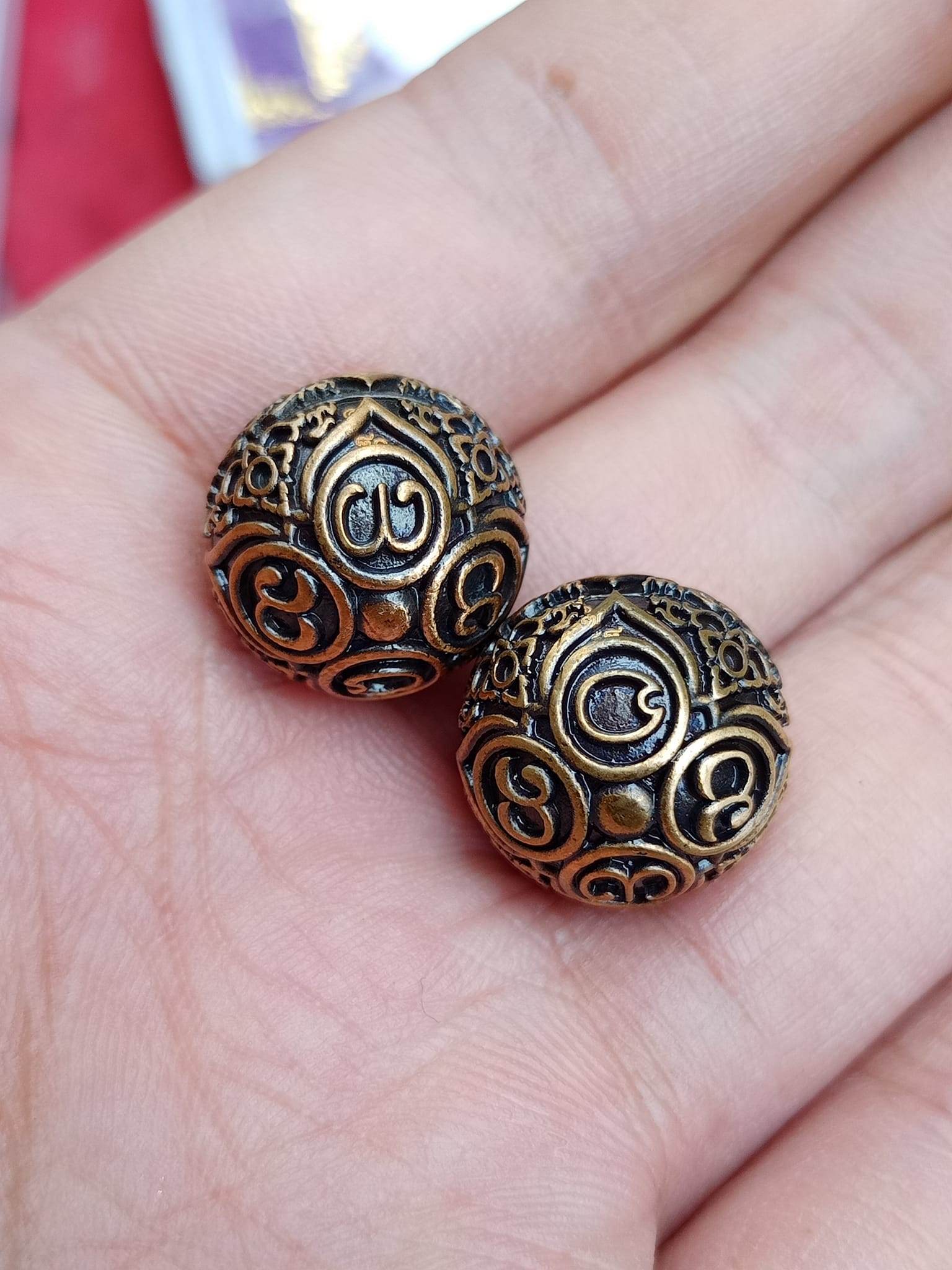 Two small ornate brass spheres with carved symbols held in hand ancient mercury spirit orb decorative amulet