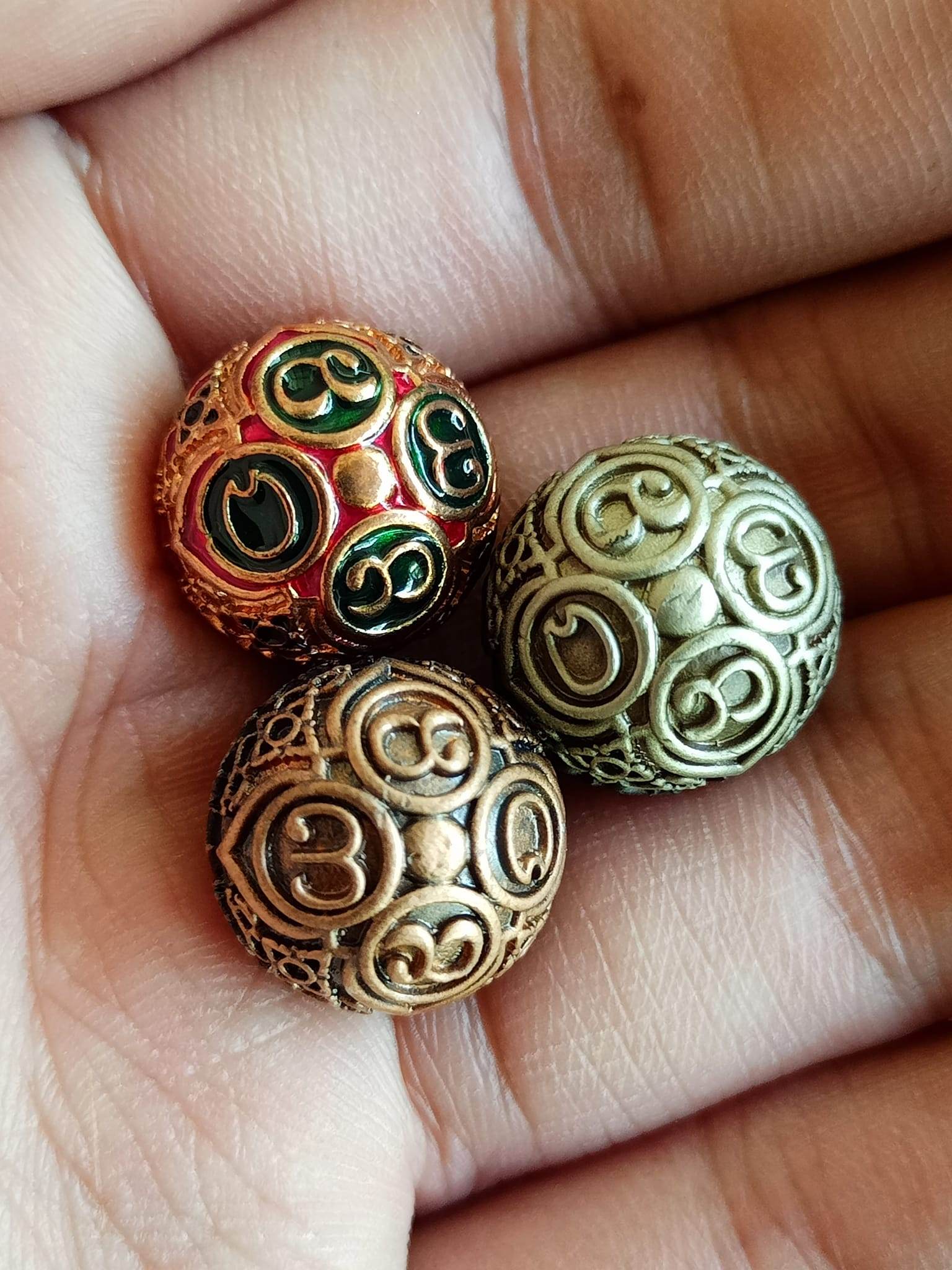 Hand holding three ornate brass feng shui balls with engraved swirls and enamel accents and ancient mercury spirit orb