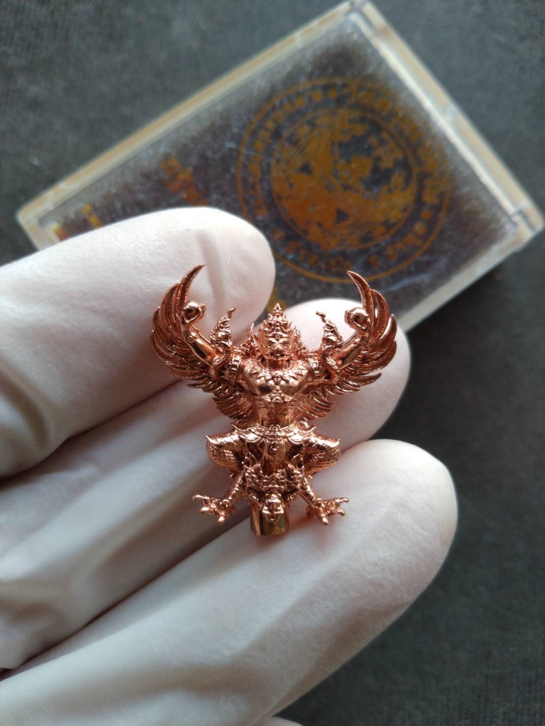 authentic Phaya Garuda lucky charm for sale copper amulet pendant shown in gloved hand with clear case