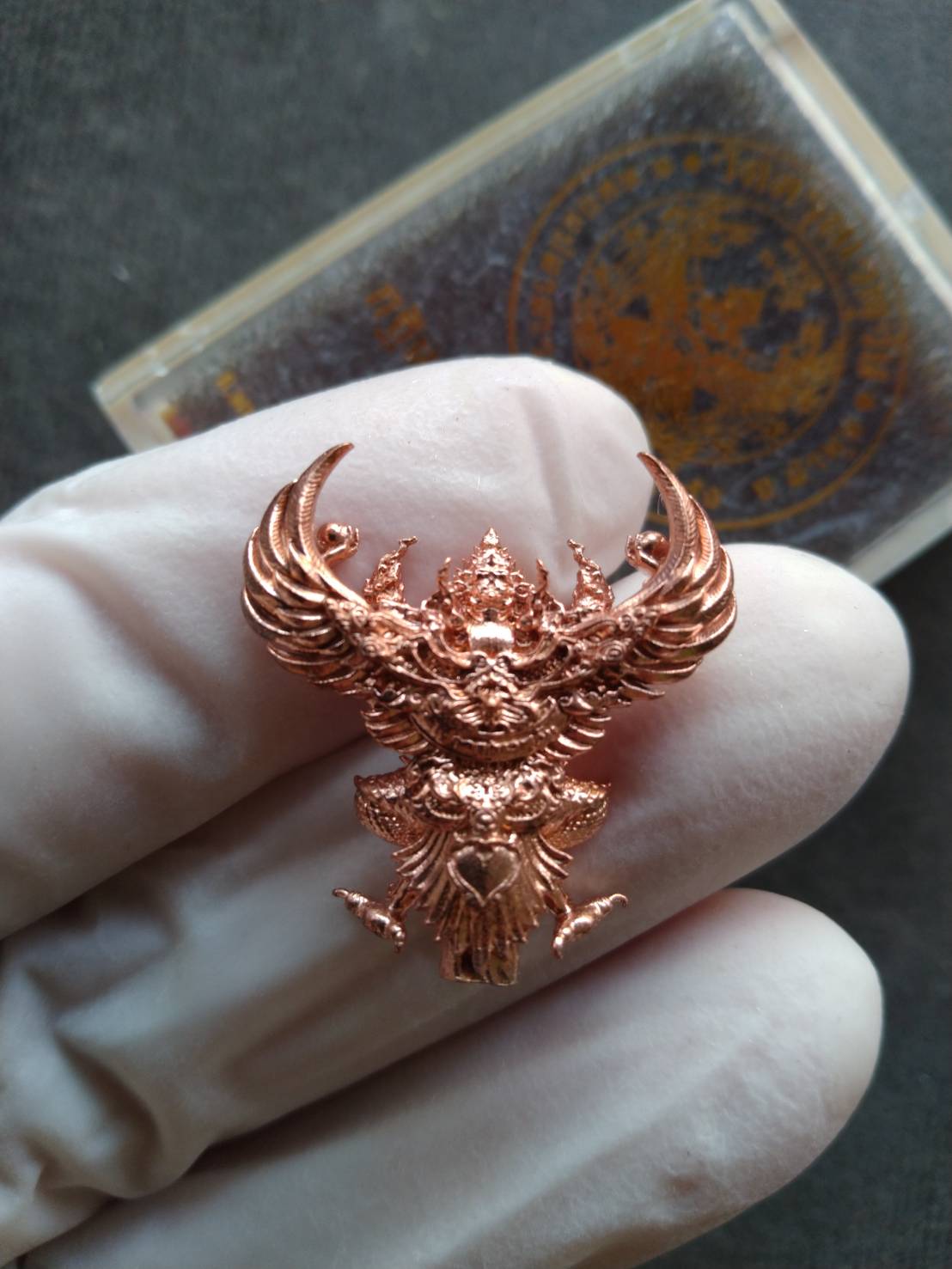 Copper Garuda amulet held in gloved hand by Thai Blessing Co authentic Phaya Garuda lucky charm for sale