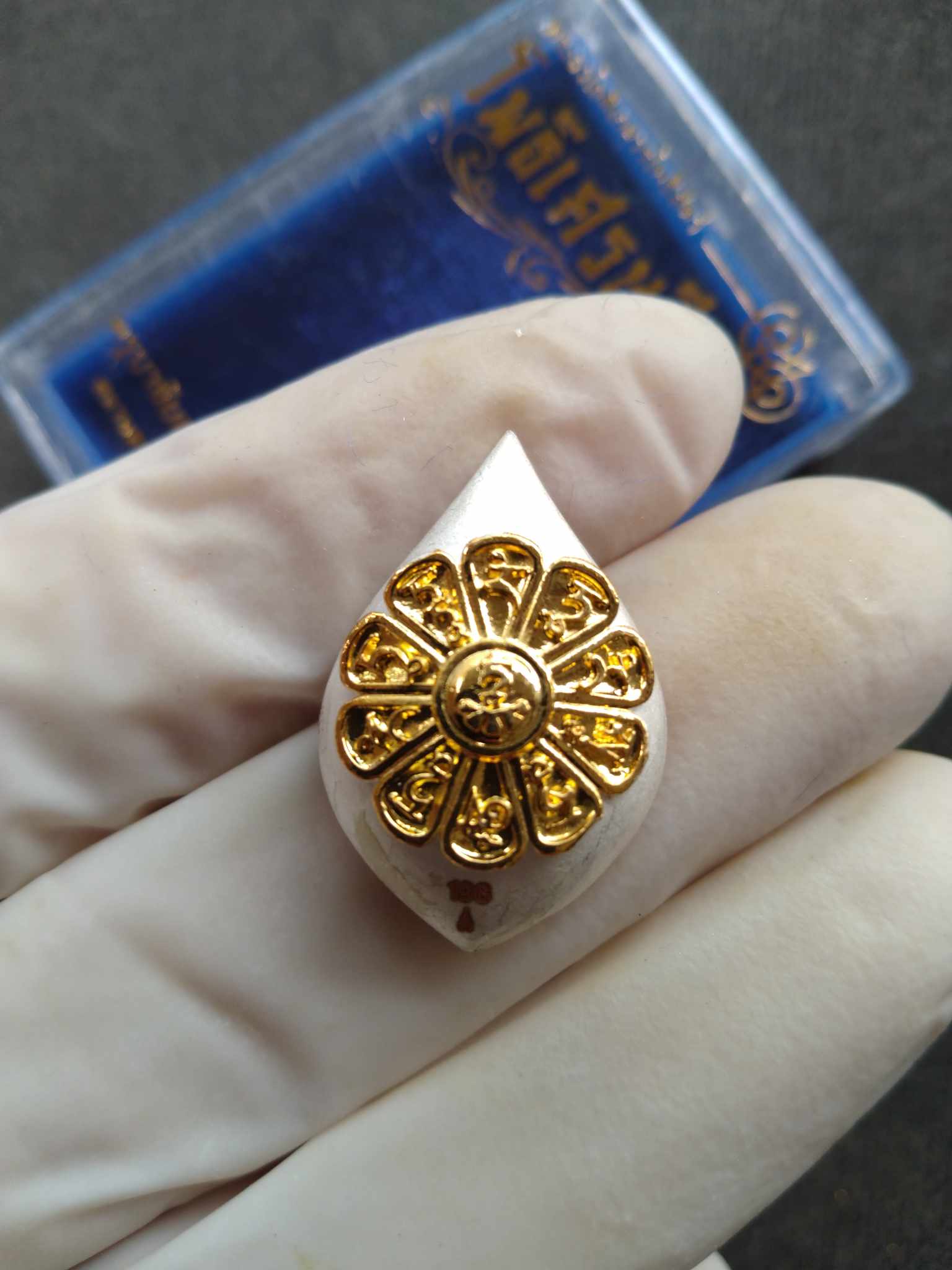 Thai Blessing Co Avalokiteshvara Bodhisattva amulet white teardrop pendant with gold lotus medallion held in gloved hand