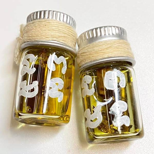Two Thai blessing oil vials with white sacred script and twine caps buy Thai spiritual charm for romance