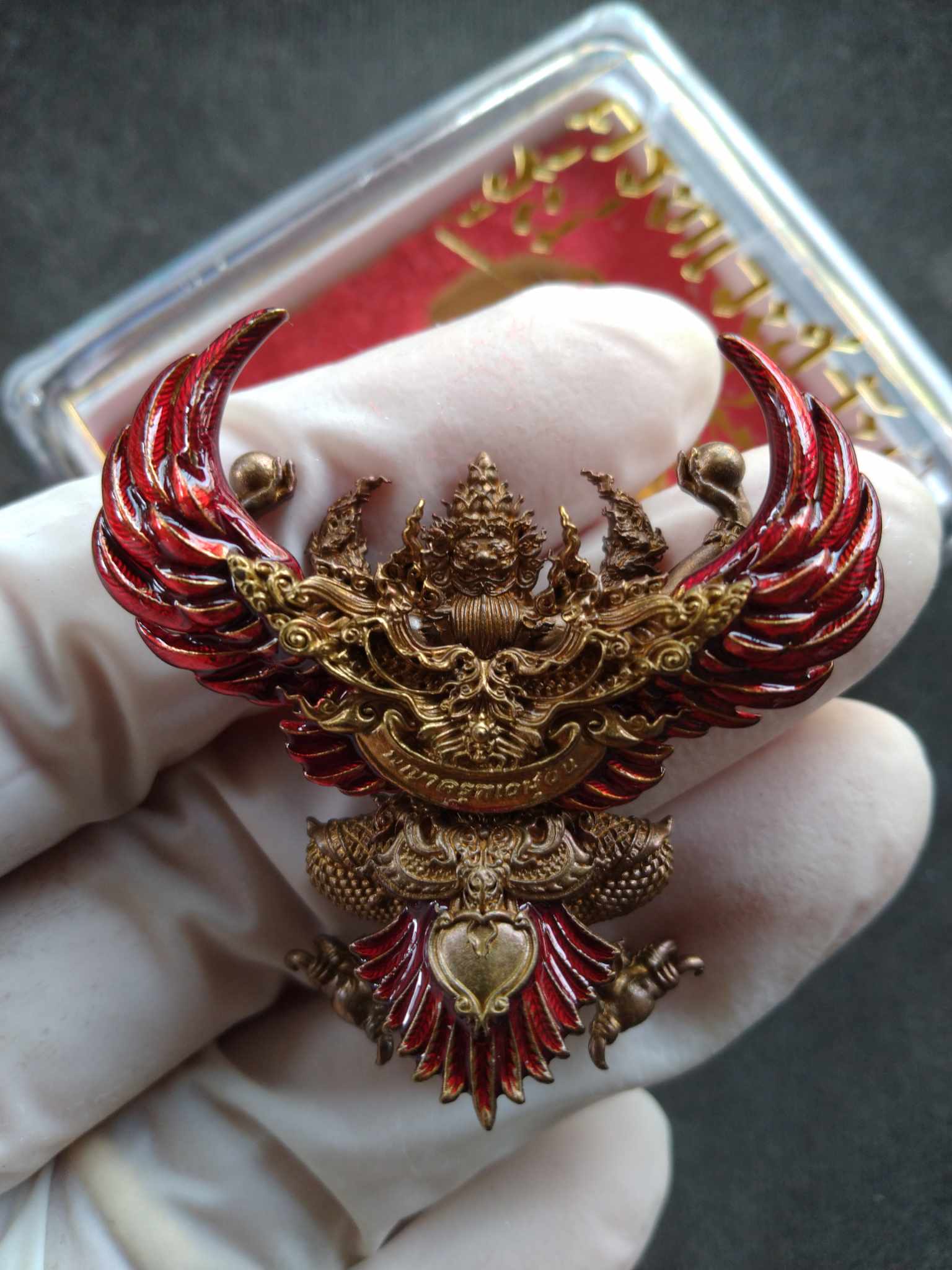 Thai Blessing Co ornate gold and red Garuda pendant held in gloved hand first edition Garuda amulet for protection