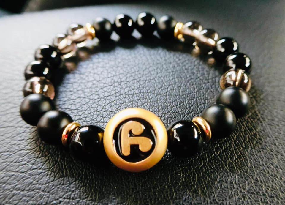 Thai amulet for protection and wealth bracelet featuring black beads and a gold emblem for positive energy