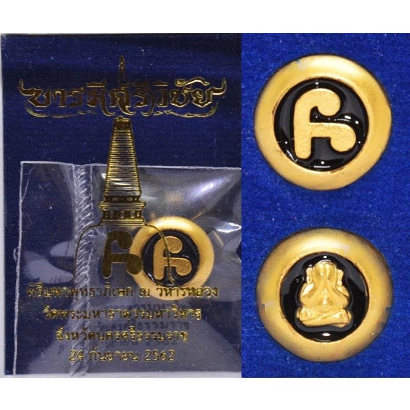 Thai amulet for protection and wealth featuring a gold symbol on a dark background in a protective package