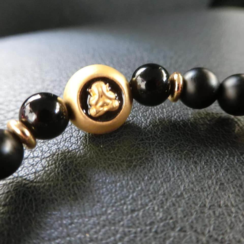 Thai amulet for protection and wealth featuring black beads and a golden centerpiece