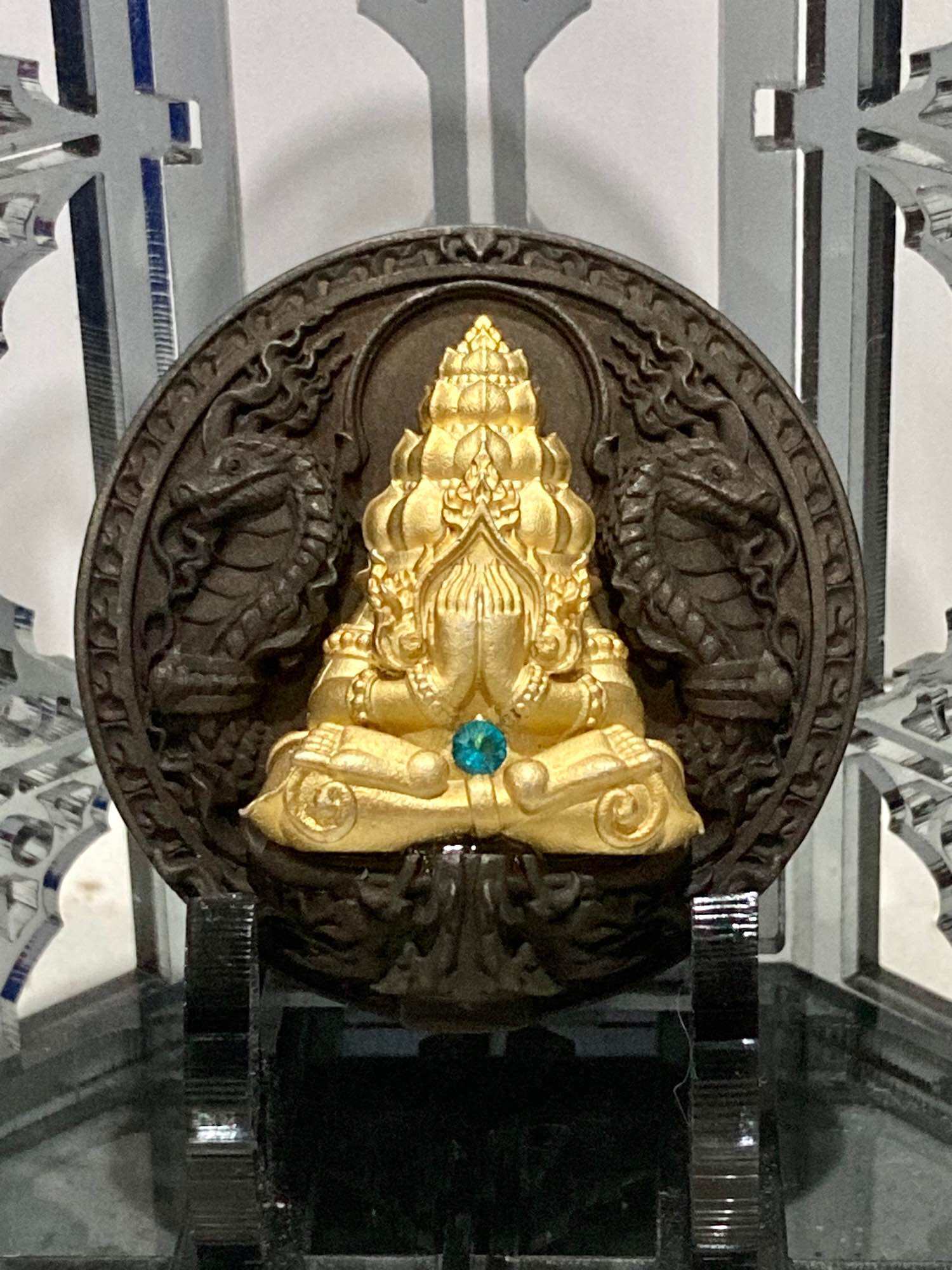 Thai amulet for wealth and protection featuring a golden deity in intricate detail