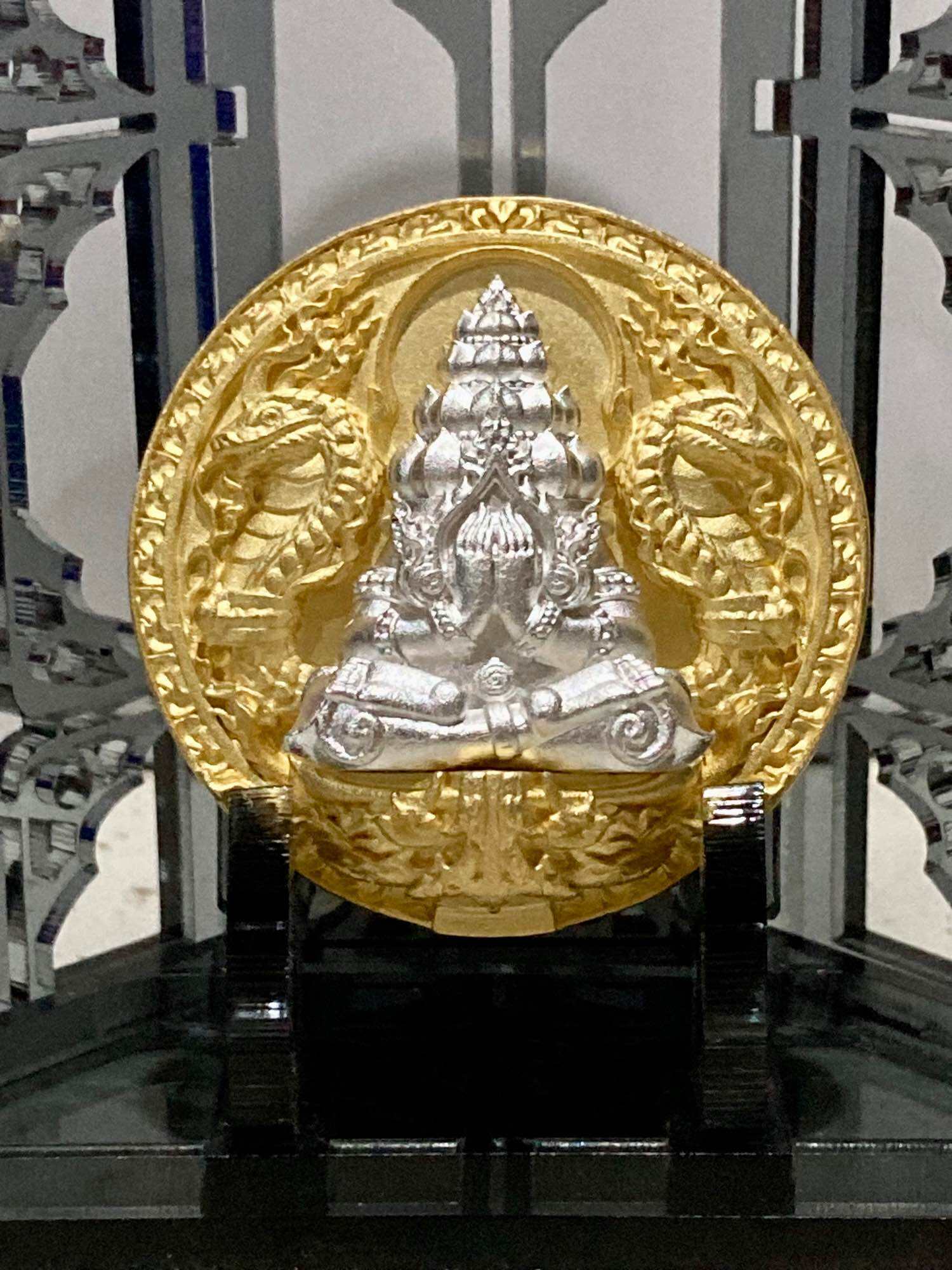 Thai amulet for wealth and protection featuring a detailed gold and silver design of a sacred figure