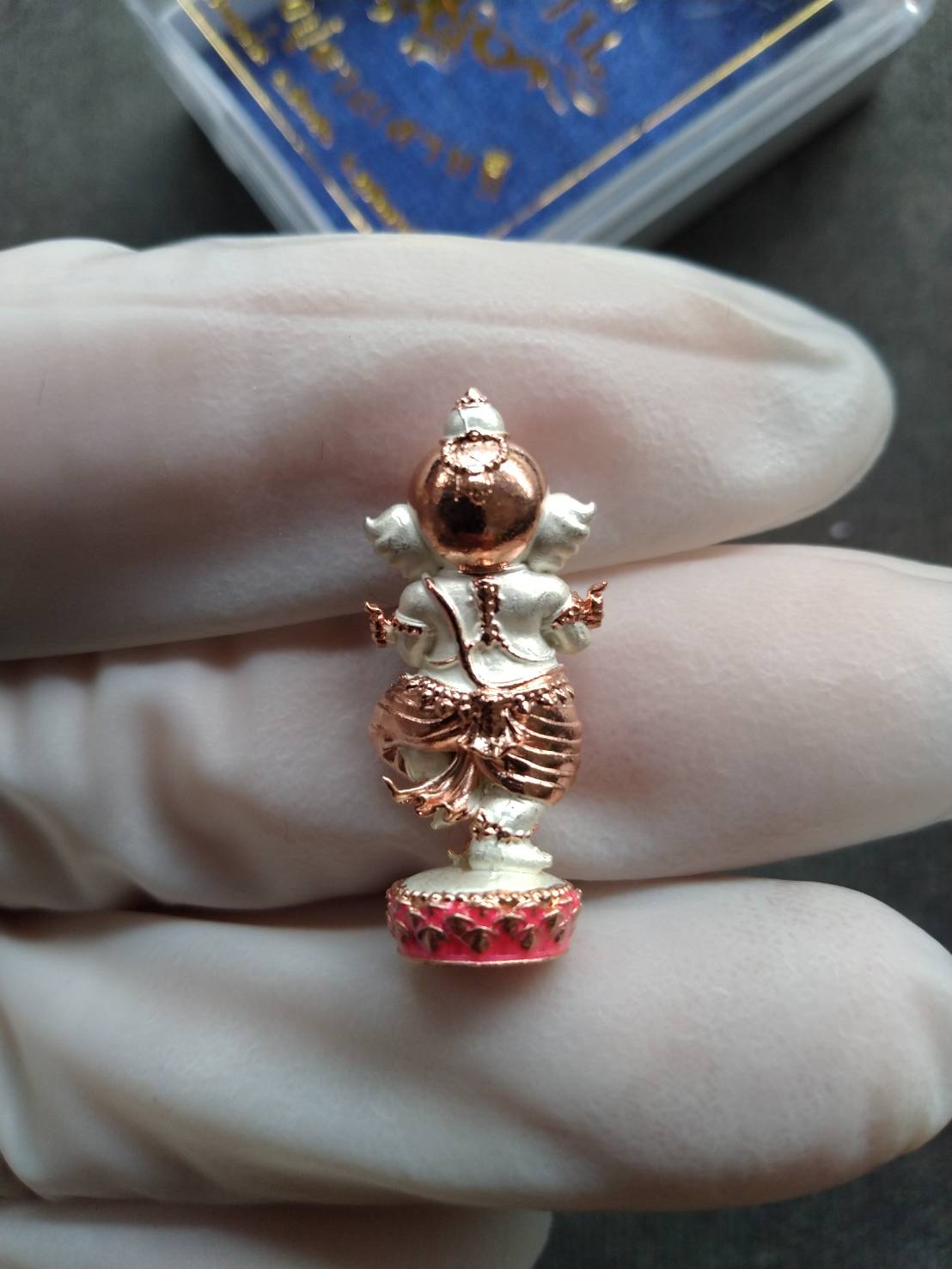 Ganesh Noi amulet Thailand two tone copper and silver Ganesha pendant on red base held by gloved hand