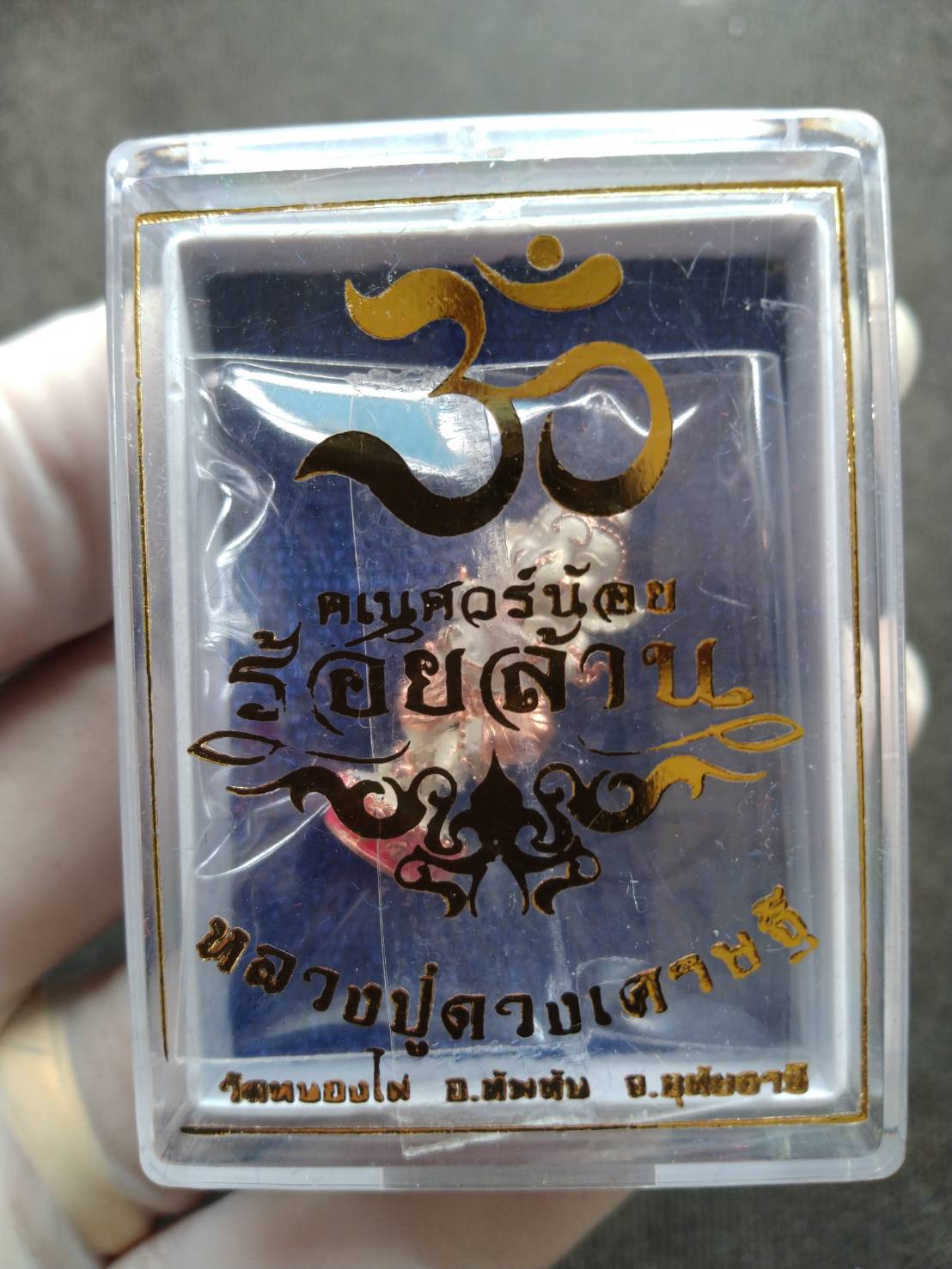 Ganesh Noi amulet Thailand in clear plastic display case with gold Om symbol and Thai script