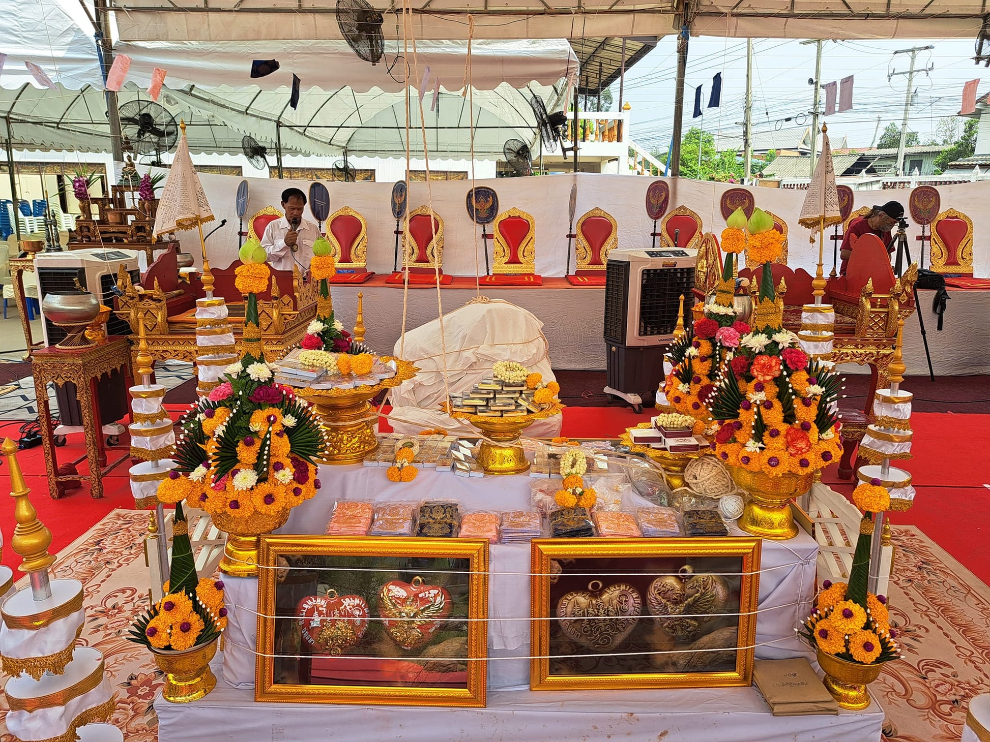 Garuda heart amulet framed pair displayed on Thai blessing ceremonial altar with gold offerings and marigold garlands