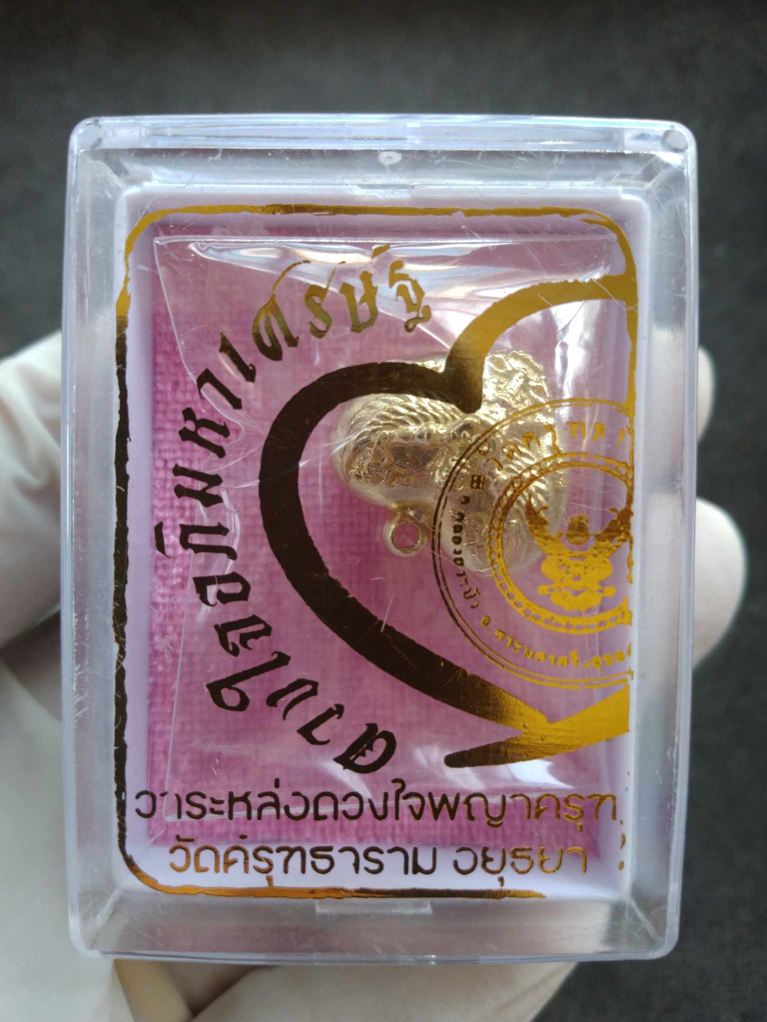 Garuda heart amulet gold pendant in clear plastic display box with pink backing card by Thai Blessing Co