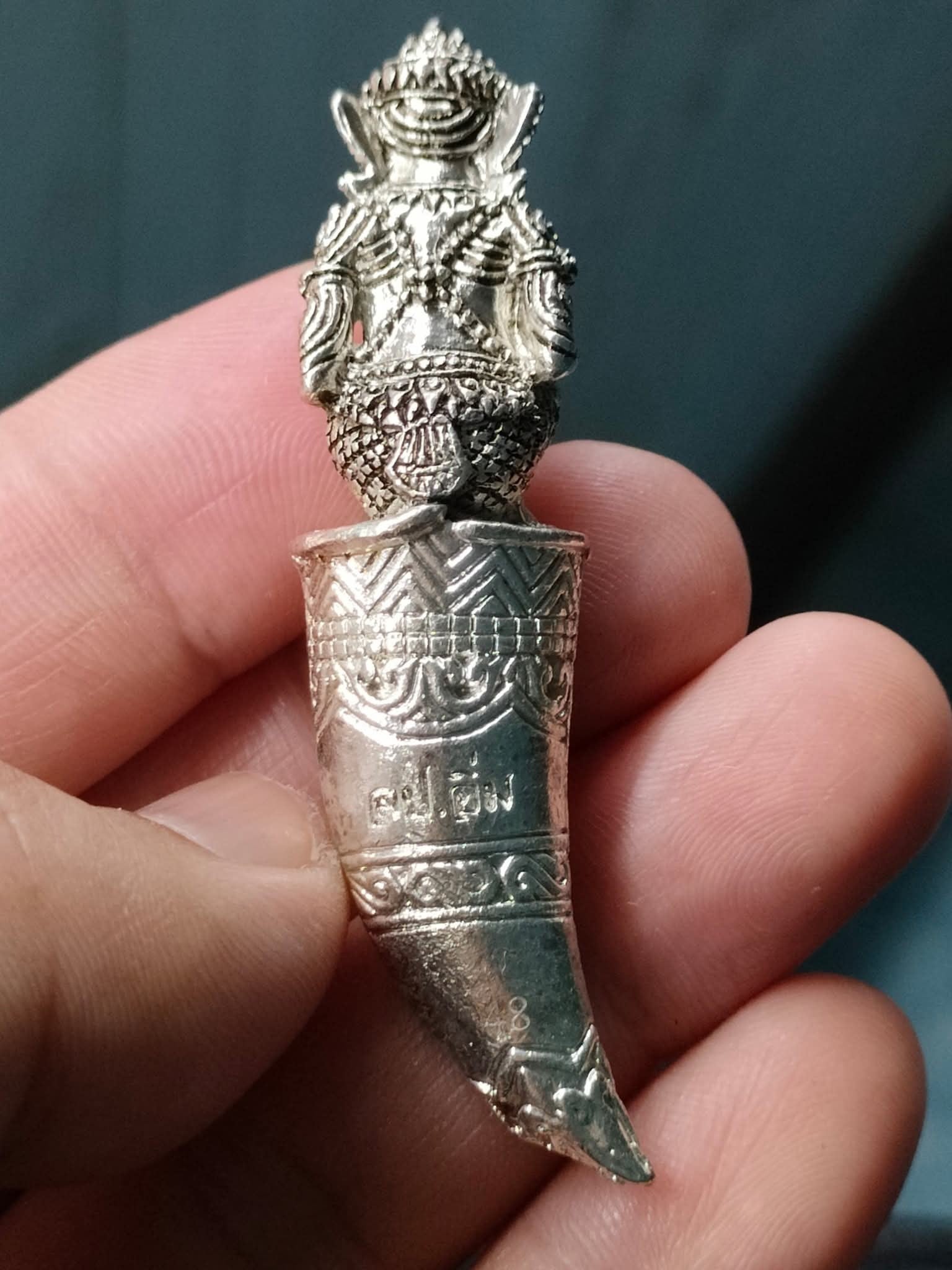 Silver amulet pendant featuring Hanuman Sitting on Fangs with Thai script held between fingers Thai Blessing Co
