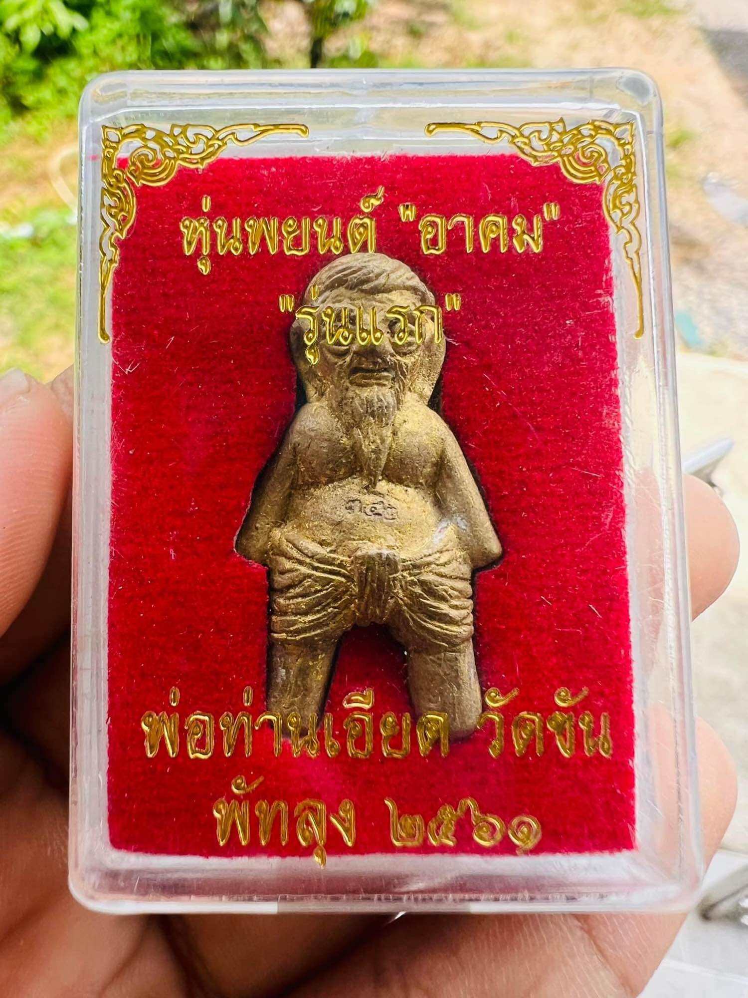 Hoon Payon ancient Thai guardian doll brass amulet in clear plastic display box on red velvet background