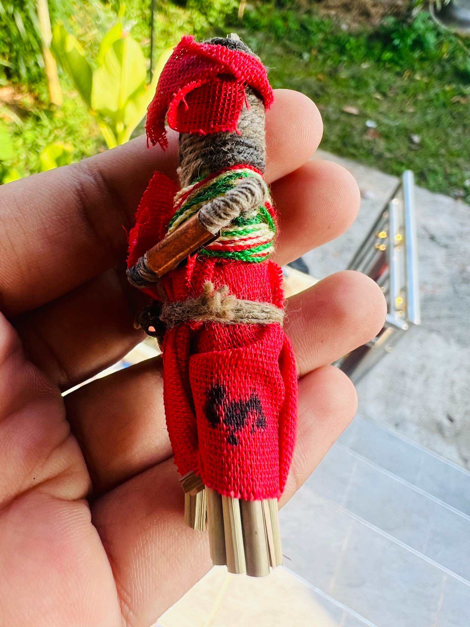 Handheld red Hoon payon sacred puppet for protection amulet wrapped in twine with bamboo stalks