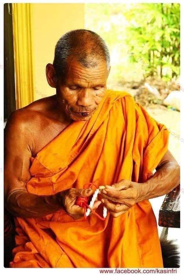 Buddhist monk inspecting a sacred amulet and beads on a porch Limited edition Thai Takrut with Luk Sakot beads.