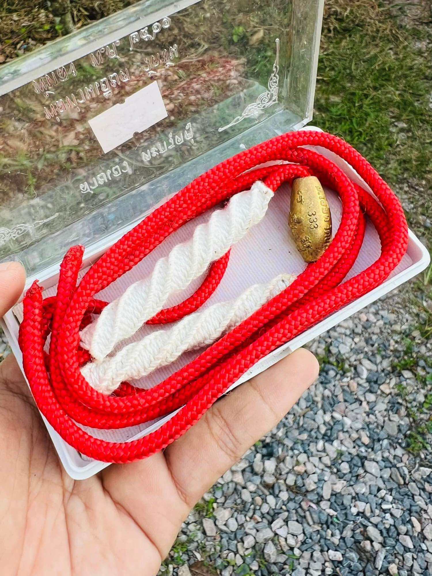 Limited edition Thai Takrut with Luk Sakot beads. Red braided cord white wrapped takrut and gold inscribed bead in clear case