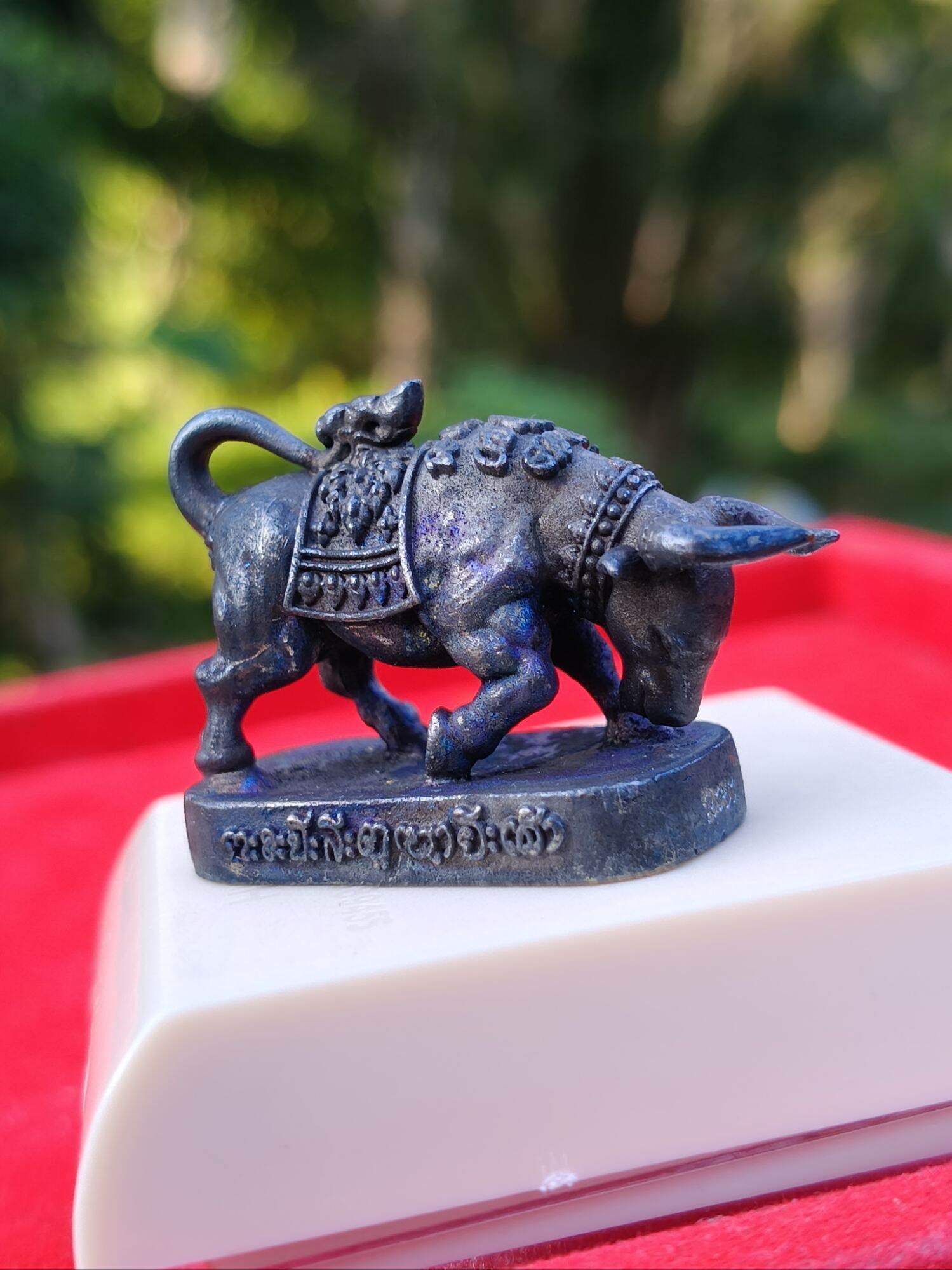 Luang Pu Lun buffalo charm for luck dark metal buffalo pendant on base with Thai script detailing