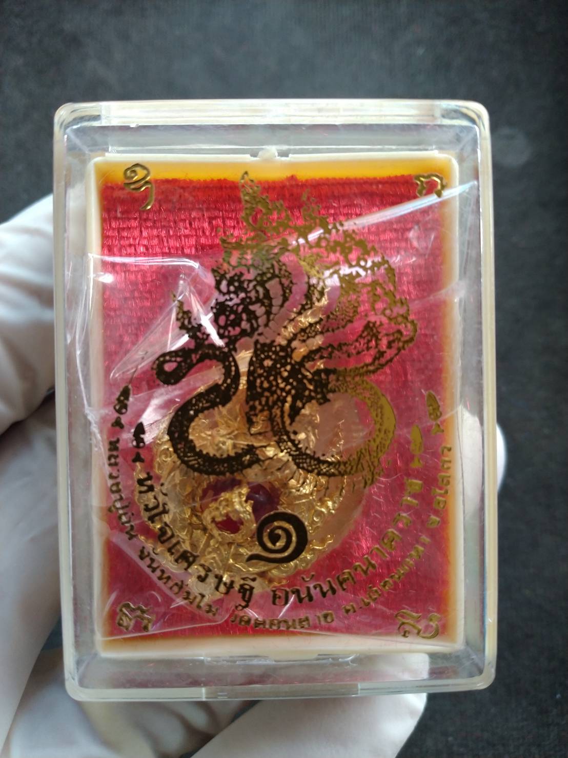 Naga King Ananta pendant gold amulet in clear plastic case on red velvet background with Thai script